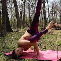 Lola Lopez in a yoga pose in the woods