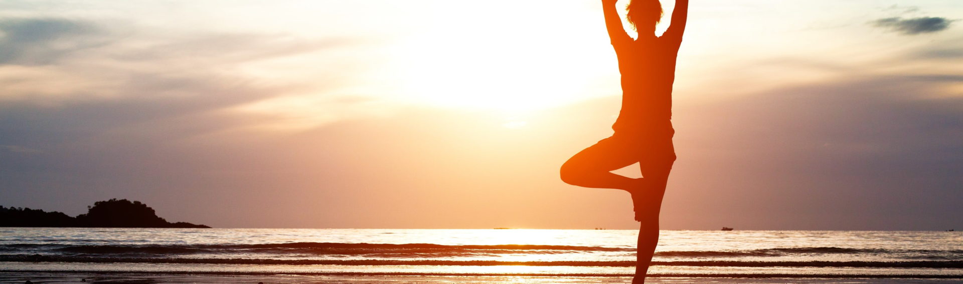 Silhouette of a person in a yoga pose on a wet beach